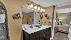 A bathroom with a double sink vanity, a large mirror, and decorative wall sconces.