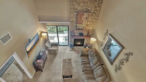 A spacious living room with a stone fireplace, a large window, and a cozy seating area.