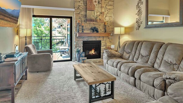 A cozy living room with a stone fireplace, a plush sofa, and a wooden coffee table.