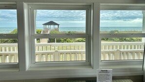 A view from a window with a gazebo and white railing, overlooking the sea.