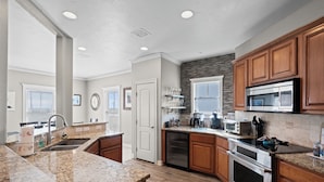 A kitchen with granite countertops, wooden cabinets, stainless steel appliances, and a dishwasher.