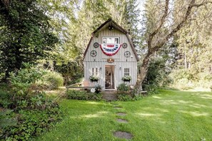 A rustic cabin with a front porch, surrounded by lush greenery. - ⭐️Wildflower Country Cottage (Oxford)