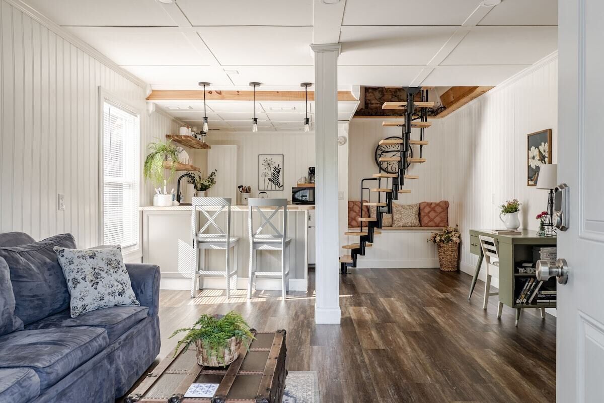 Un salon moderne avec un canapé, une table basse et un escalier menant à un niveau supérieur.