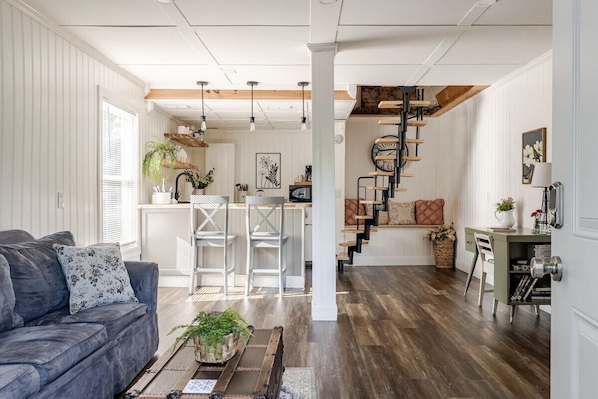 A modern living room with a sofa, coffee table, and a staircase leading to an upper level.