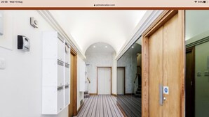 A hallway with a striped carpet, white walls, and wooden doors.