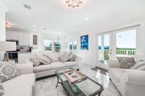 Relax in this stylish living room with a large sofa, sleek TV, and kitchen area.