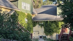 A two-story house with a green exterior, a sloped roof, and a visible window. - VACATION RENTAL- SLEEPS UP TO 10 -GOLDEN BC (Blaeberry)