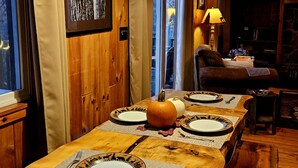 Une table de salle à manger en bois, mise avec des assiettes, une citrouille et une lampe.