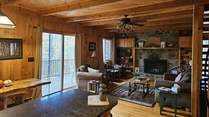 L’intérieur d’un chalet en bois comprend une cheminée en pierre, un coin repas et un espace salon confortable.