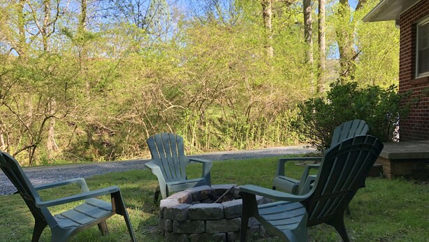 Un patio con sillas Adirondack y un hogar a fuego de piedra.