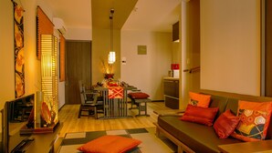 A hotel room with a dining area, a sofa with red cushions, and a wooden floor. - Samurai House (Nagoya)