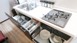 A compact kitchen with a gas stove, a sink, and a dish rack. - Samurai House (Nagoya)