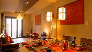 A dining area with a table set for two, featuring traditional Japanese decor and a television. - Samurai House (Nagoya)