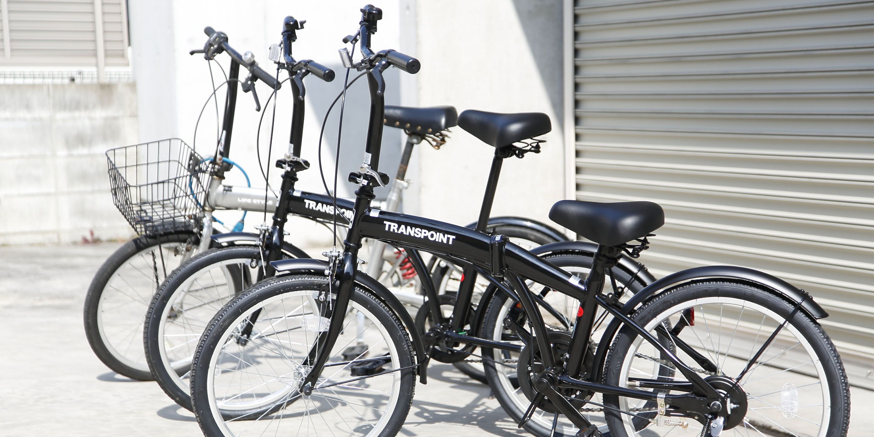 A row of bicycles parked outside a building with a metal shutter door.