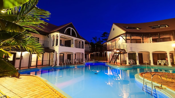 A swimming pool surrounded by two-story buildings with balconies, a covered area, and a wooden deck. - The Pool Resort Villa ICHIGOICHIE (Onna)