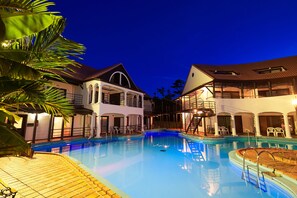 A swimming pool surrounded by two-story buildings with balconies, a covered area, and a wooden deck. - The Pool Resort Villa ICHIGOICHIE (Onna)