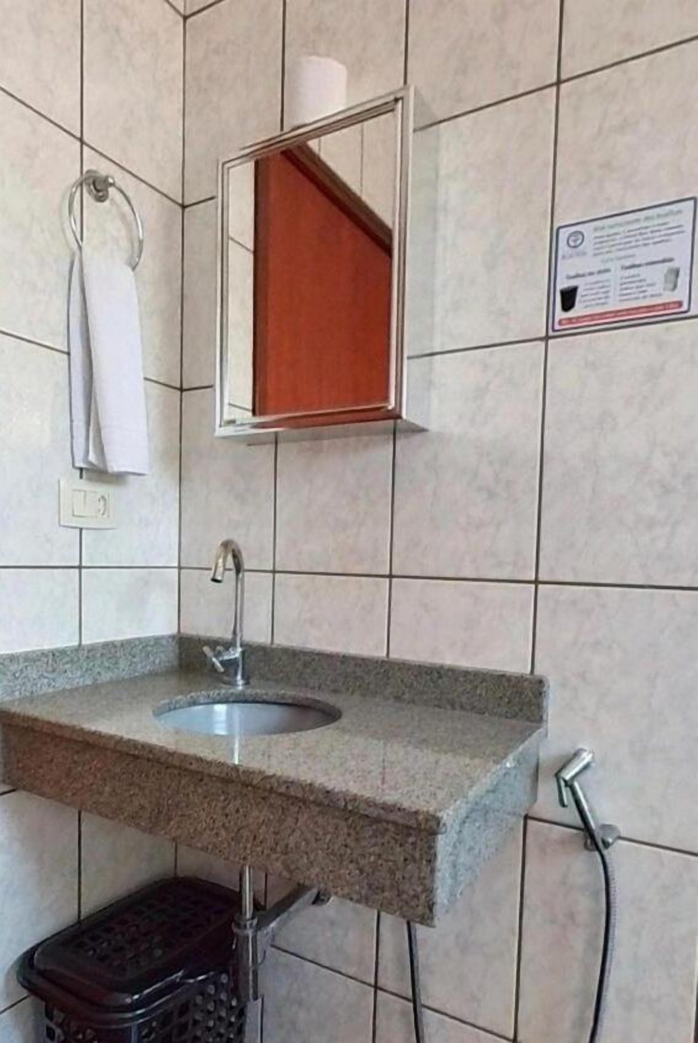 Baño con lavamanos de encimera de granito, espejo, toallero y basurero.