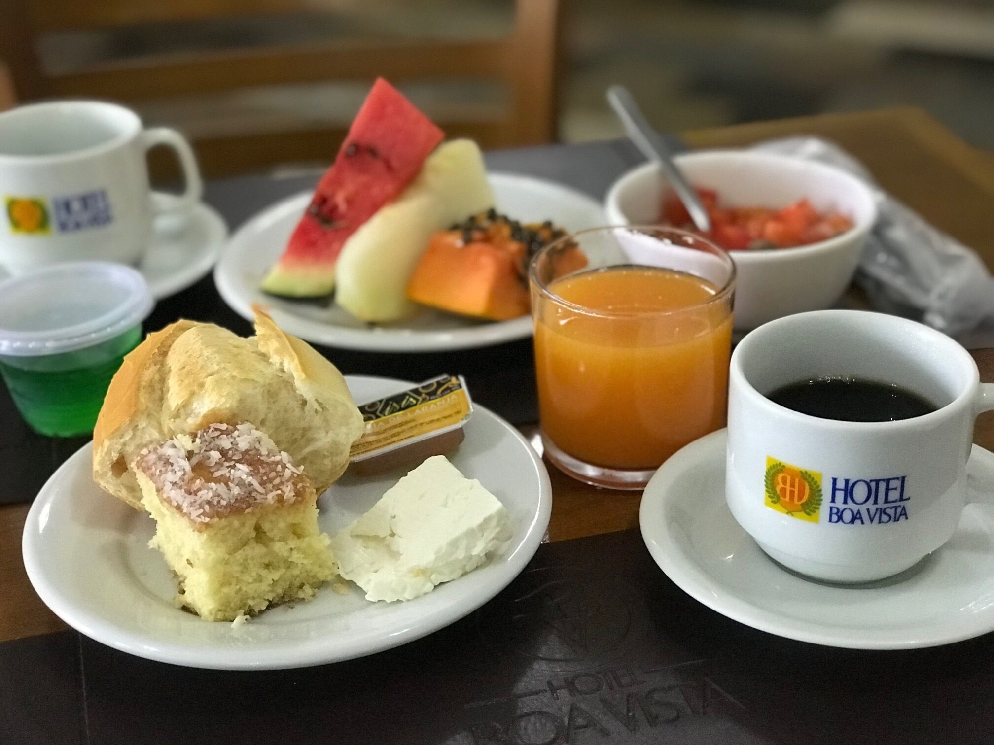 A breakfast setting with a plate of food, a glass of orange juice, a cup of coffee, and a bowl of fruit.