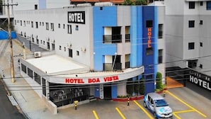 Un hotel con un cartel que dice "HOTEL BOA VISTA" y un estacionamiento con un coche.