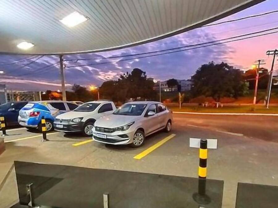 A gas station with multiple cars parked, a clear sky, and a building with a visible logo.