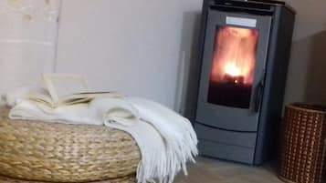 Una habitación con un otoman tejido, un libro y una manta blanca.