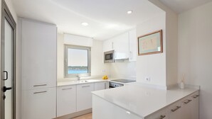 A modern kitchen with white cabinets, a microwave, and a window overlooking a scenic view.