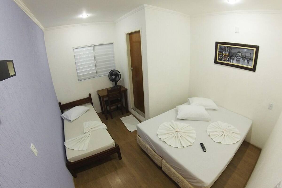 A small, clean room with two single beds, a desk, and a chair.