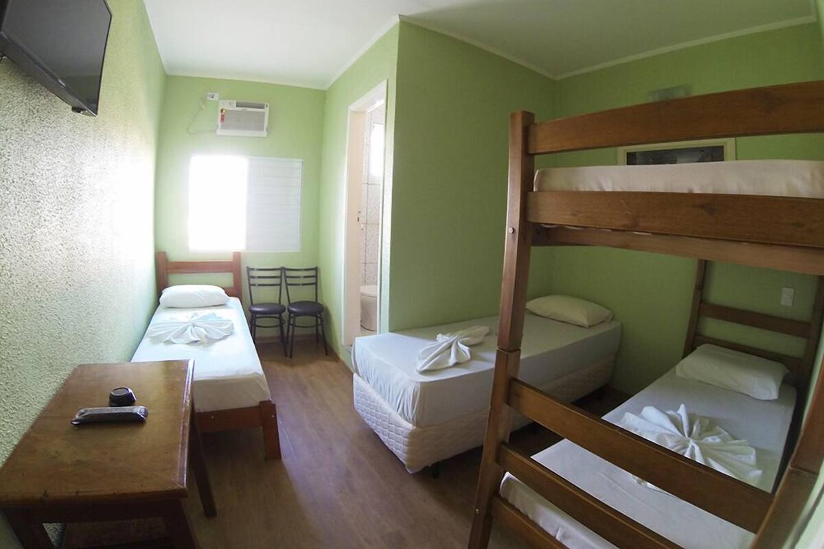 A room with two single beds, a bunk bed, a small table, and a chair.