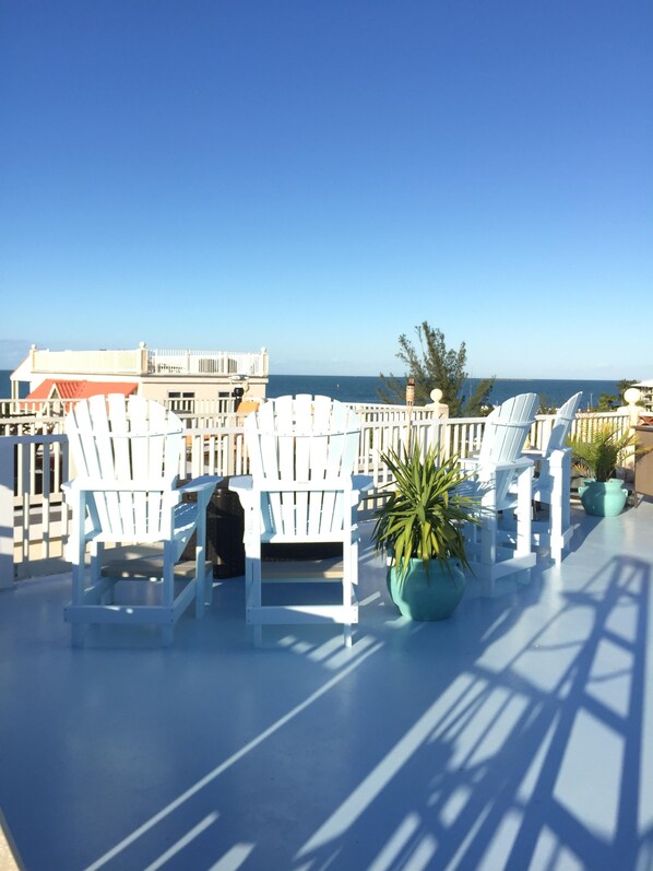 A terrace with white Adirondack chairs and potted plants, overlooking a coastal view. - Views ~ Pool~Private Hot Tub~FREE Boat Slip~Heaven!!! (Marathon)