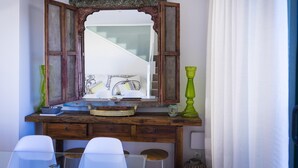 A wooden vanity with a mirror, a sink, and a green vase.