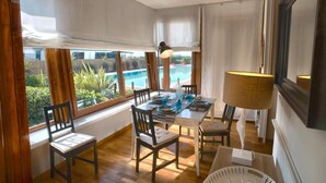 A dining area with a pool view, wooden furniture, and a large lamp. - La Vue Sur La Mer Beach House (Viareggio)
