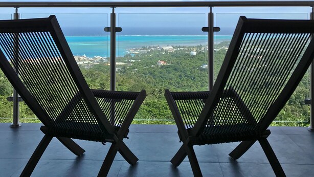 Two lounge chairs facing a scenic ocean view from a balcony. - Summit Condominium and Hotel (Saipan)