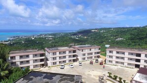 A multi-story residential building with a parking area in front. - Summit Condominium and Hotel (Saipan)