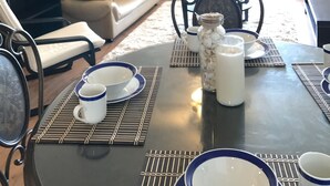 A dining area with a table set for four, a sofa, a TV, and a plant. - Summit Condominium and Hotel (Saipan)
