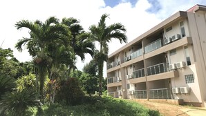 A multi-story building with balconies, surrounded by lush greenery and palm trees. - Summit Condominium and Hotel (Saipan)