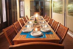 A dining table set for a meal with chairs, plates, glasses, and a candle centerpiece.