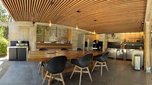 A modern kitchen with a wooden ceiling, a central island with chairs, and stainless steel appliances.