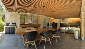 A modern kitchen with a wooden ceiling, a central island with chairs, and stainless steel appliances.