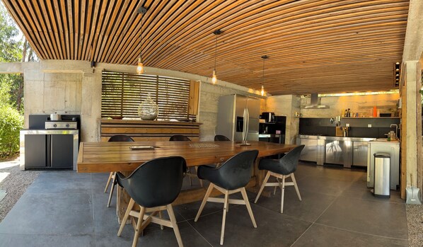 Una cocina moderna con techo de madera, una isla central con sillas y electrodomésticos de acero inoxidable.