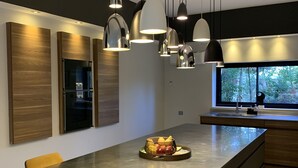 A modern kitchen with a large island, pendant lighting, and a view of the outdoors.