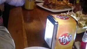 Una zona de bar con diversos alimentos en la barra, incluyendo una caja de jugo TDNa, un tarro de mostaza y varias fuentes de comida.