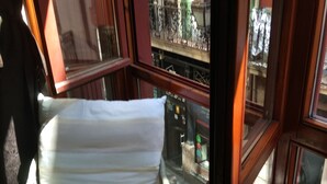 Una habitación con cama de paredes de cristal, vistas a la calle y suelo de madera.