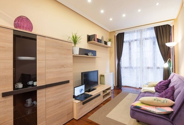 A modern living room with a sofa, TV, and built-in entertainment unit.