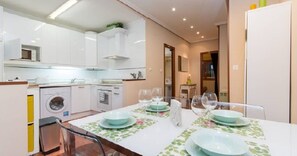 A modern kitchen with white cabinets, a washing machine, and a dining area with a table set for four. - Apt old town in Artekale street,<br> pedestrian, optional parking for a fee (Bilbao)