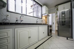 A kitchen with white cabinets, a stainless steel refrigerator, and a window with a view of the outside.