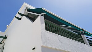 A building with a white exterior, a green awning, and a visible window with a metal grill.