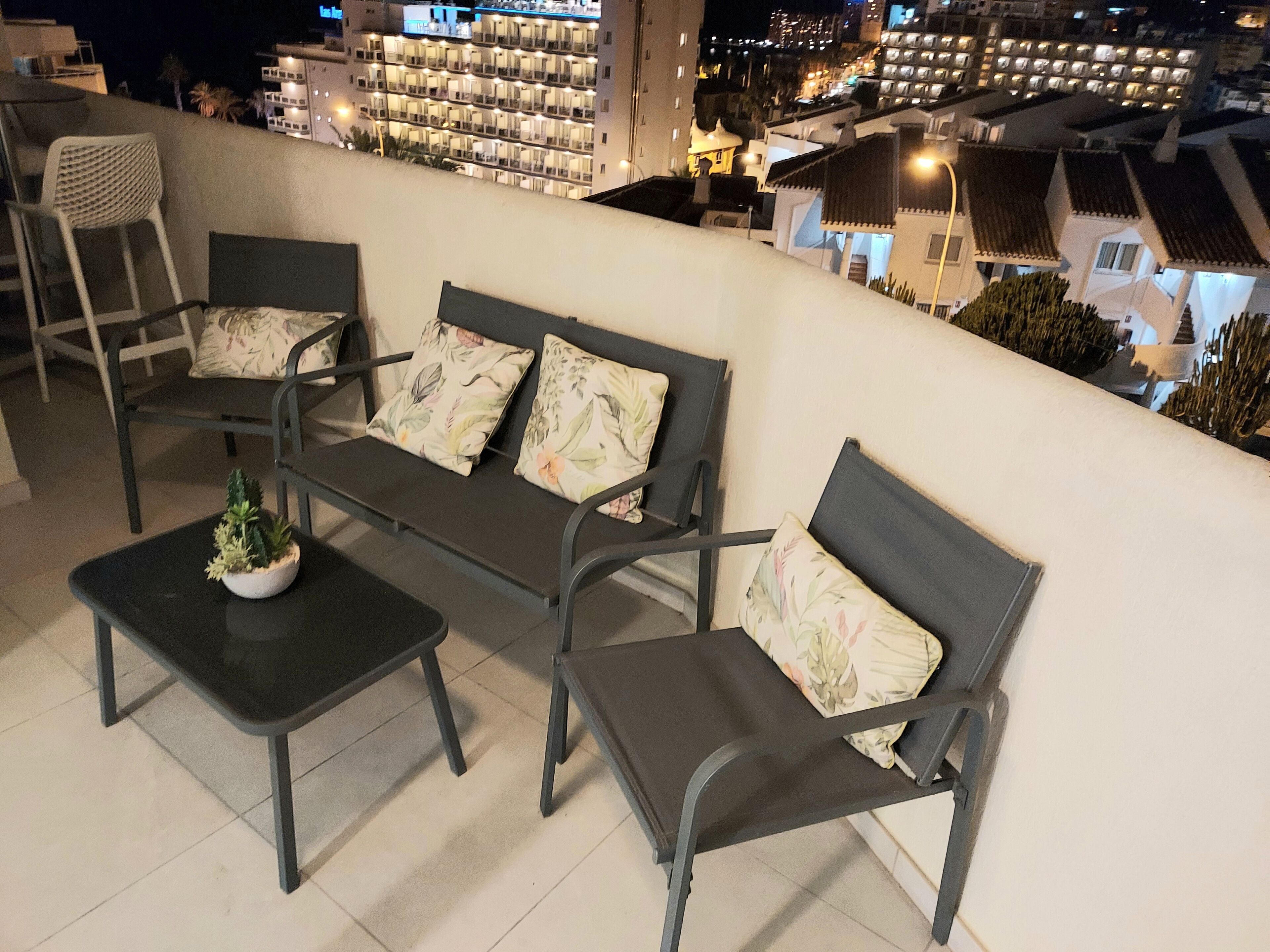 A balcony with a sofa set, a small table with a plant, and a chair.
