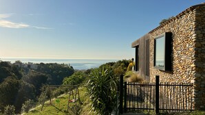 A modern building with a stone facade and large windows overlooking a coastal landscape.