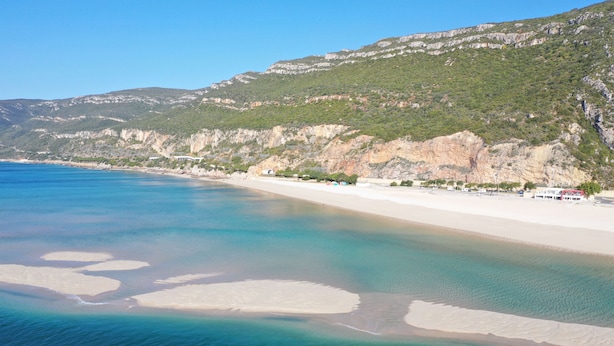 A coastal beach with clear waters, a sandy shore, and a mountainous backdrop. - Rural farm Enjoy nature and feel the silence (Palmela)