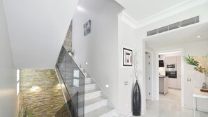 Um interior moderno com escadaria de vidro, área de cozinha e espaço para refeições.